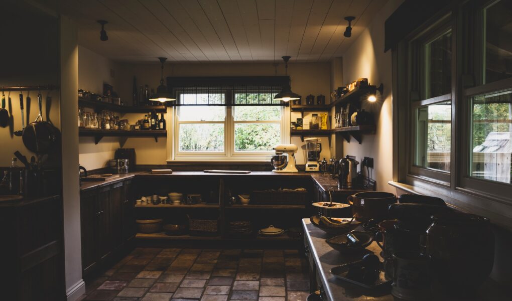 Interior view of kitchen with stone tile floor, wooden ceiling and two sash windows, antique wooden
