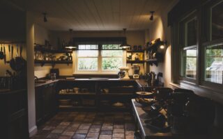 Interior view of kitchen with stone tile floor, wooden ceiling and two sash windows, antique wooden