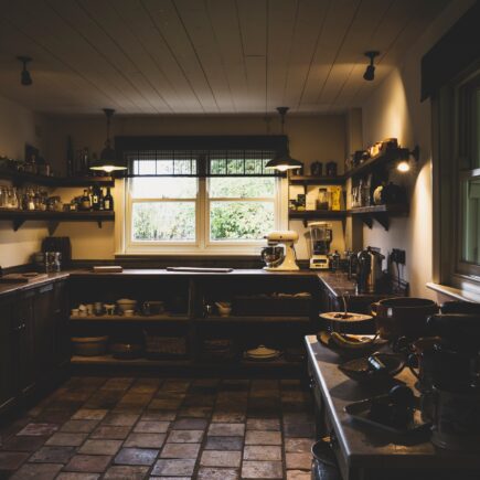 Interior view of kitchen with stone tile floor, wooden ceiling and two sash windows, antique wooden