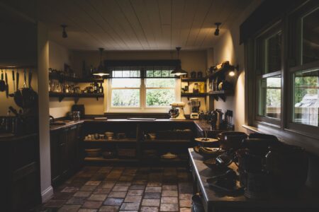 Interior view of kitchen with stone tile floor, wooden ceiling and two sash windows, antique wooden