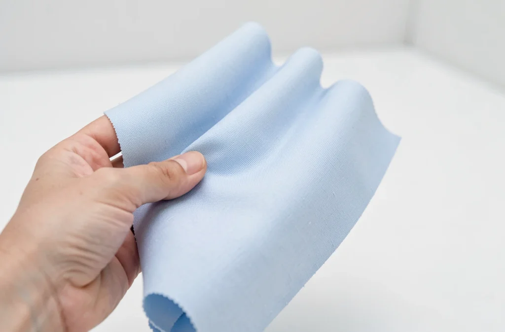 Main tenant des échantillons de tissu bleu clair et bleu poudre comparés sur fond blanc